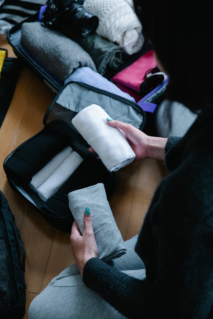 services-01 Person packing and organizing clothes in a suitcase for travel.