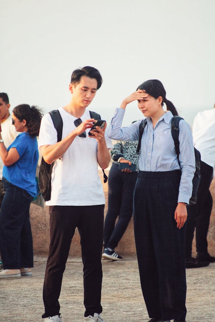 Two adults using smartphone for navigation while sightseeing outdoors. Casual travel scene.