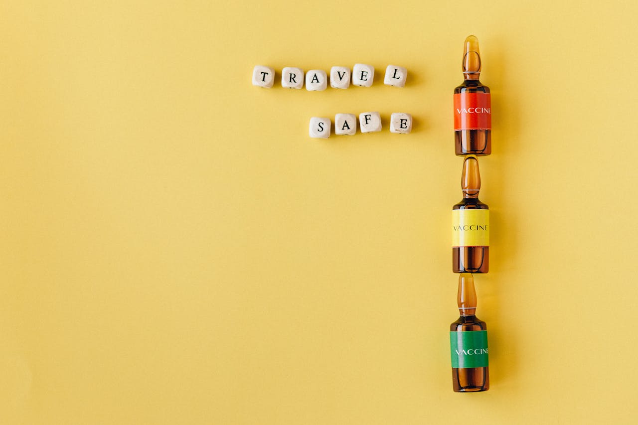 Three vaccine vials with a Travel Safe message arranged on a yellow background, conveying safety and health themes.